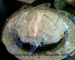 pumpkin cake covered with Cling Wrap supported on toothpicks