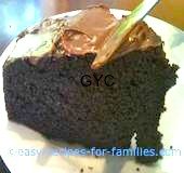A slice of cake from easy chocolate cake recipes, with frosting being spread