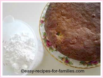 sultana cake with a jug of icing sugar